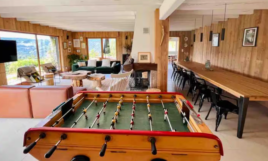 Grande pièce de vie d'un chalet avec baby-foot et longue table en bois